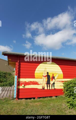 Rote Hütte mit Graffito, zwei Surfer vor Sonnenuntergang, Sylt, Nordfriesische Inseln, Schleswig-Holstein, Deutschland Stockfoto