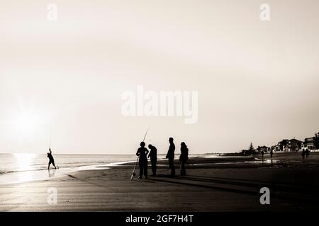 Menschen fischen Silhouette am Strand Stockfoto