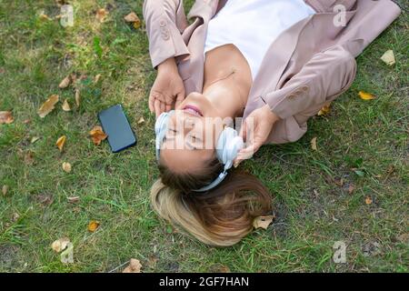 Nahaufnahme - Frau im Gras genießt die Musik. Draufsicht. Stockfoto