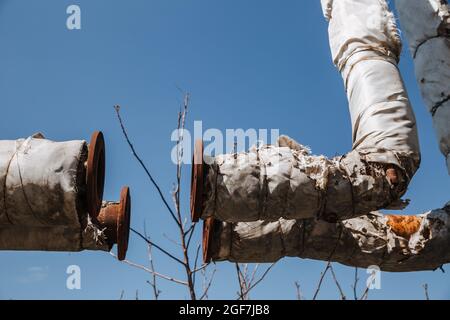 Defekte Wärmedämmung der Stadtwasserversorgung. Veraltete Technologie. Zerstörte Infrastruktur, oberirdische Wärmerohre. Stockfoto