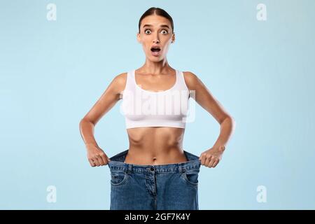 Schockiert Skinny Frau Ziehen Ihre Alte Große Lose Jeans Stockfoto