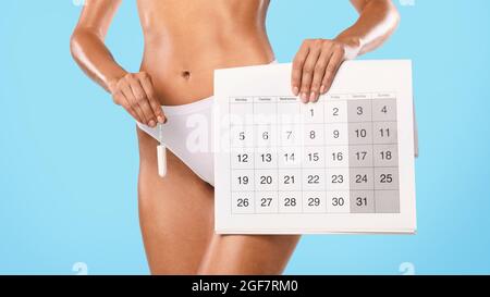 Lady hält Kalender und Tampon isoliert auf blauem Studiohintergrund Stockfoto