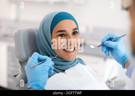 Lächelnde Muslimische Frau In Hijab Beim Zahnarzt In Der Klinik Stockfoto