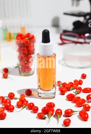 Goji-Beerensamenöl in Glasflasche und frische Goji-Beeren auf dem Tisch. Stockfoto