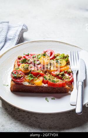 Toast mit Tomaten, Pesto-Sauce und Frischkäse, Nahaufnahme. Italienisches Küchenkonzept. Stockfoto