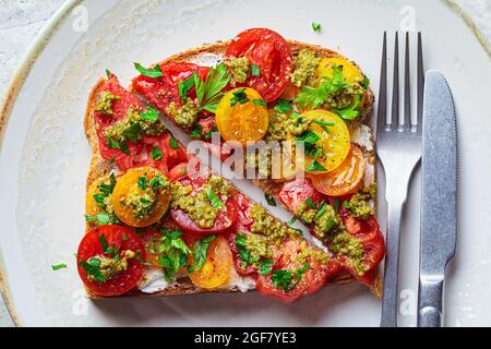 Toast mit Tomaten, Pesto-Sauce und Frischkäse, Nahaufnahme. Italienisches Küchenkonzept. Stockfoto