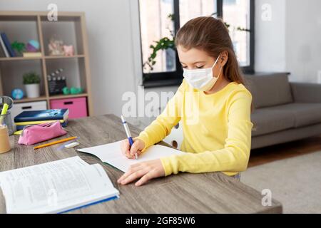 Student Mädchen in medizinische Maske zu Hause lernen Stockfoto