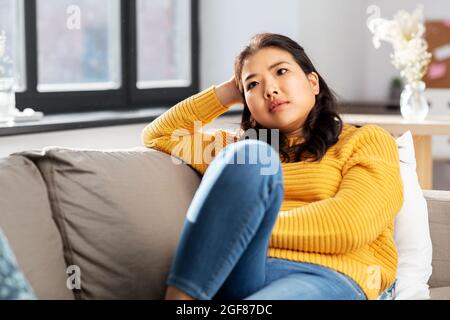 Besorgt asiatische junge Frau sitzt auf dem Sofa zu Hause Stockfoto