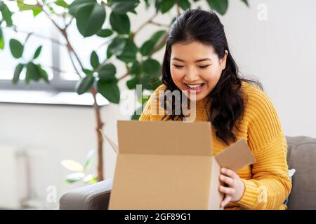 glückliche junge Asiatin mit Paketbox zu Hause Stockfoto