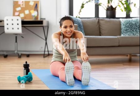 afrikanische Frau mit sich zu Hause dehnenden Kopfhörern Stockfoto