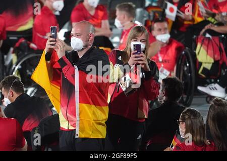 Tokio, Japan. August 2021. Paralympics: Eröffnungsfeier im Olympiastadion. Die Athleten des Teams Deutschland kamen bei der Eröffnungsfeier an den ihnen zugewiesenen Plätzen an. Dennis Nohl, Nationaltrainer der Rollstuhlbasketballmannschaft der Frauen, und Fahnenträger Mareike Miller, ein Rollstuhlbasketballspieler, fotografieren mit ihren Mobiltelefonen. Quelle: Karl-Josef Hildenbrand/dpa/Alamy Live News Stockfoto