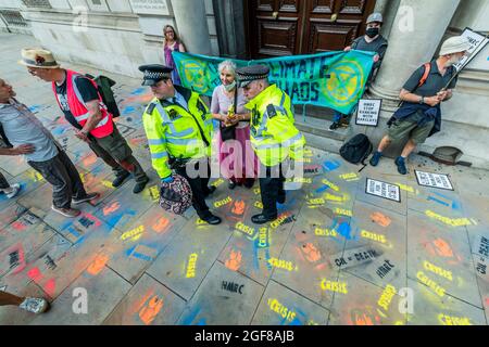 London, Großbritannien. August 2021. Anti-Barclays und Anti-Öl-Worte werden auf den Bürgersteig vor den Büros des HMRC gesprüht die Polizei sammelt die Spraydosen und warnen einige der Demonstranten - XR Cymru protestiert vor HM Revenue and Customs in Whitehall über die Regierungen, die mit der fossilen Energiewirtschaft zu tun haben, und auch Barclays Aufzeichnungen darüber Finanzierung - Extinction Rebellion startet zwei Wochen lang unter dem Namen Impossible Rebellion in London. Kredit: Guy Bell/Alamy Live Nachrichten Stockfoto