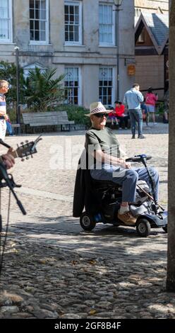 Truro, Großbritannien. August 2021. Die Menschen nutzen den herrlichen Sonnenschein in Truro, Cornwall. Ein Mann in einem Motorroller saß vor der atemberaubenden Kathedrale und hörte Musik. Die Prognose ist für 19C, sonnige Intervalle und eine leichte Brise. Kredit: Keith Larby/Alamy Live Nachrichten Stockfoto