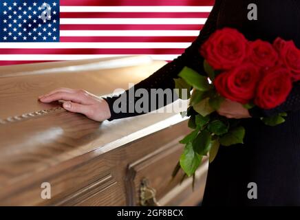 Frau mit roten Rosen und Sarg über amerikanischer Flagge Stockfoto