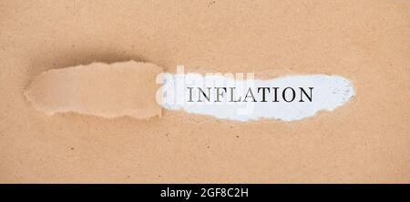 Das Wort Inflation steht auf einem weißen, zerrissenen Papier Stockfoto