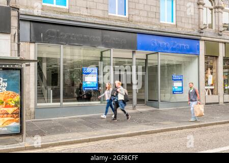 Menschen (Bewegungsunschärfe), die an leeren Geschäften in der geschlossenen Schuhzone und der Clearance Zone in der Union Street, Aberdeen, vorbeigehen. Stockfoto