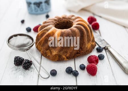 Kuchen. Marmorkuchen Tasse Kaffee Pulver Zucker Küche vintage Utensil und frische Obstbeeren. Stockfoto