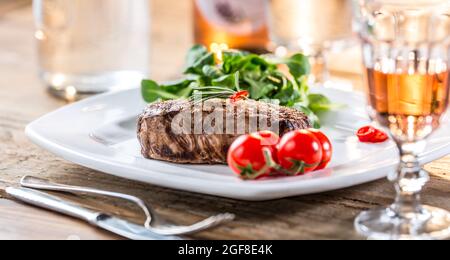 Rindersteak. Saftiges Rindersteak. Gourmet-Steak mit Gemüse und einem Glas Rosenwein auf einem Holztisch. Stockfoto