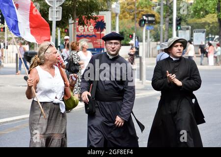 Marseille, Frankreich. August 2021. Kirchenmänner laufen während der Demonstration an einer Frau mit der Flagge Frankreichs vorbei.Tausende von Menschen demonstrierten gegen den Gesundheitspass in Marseille, Frankreich. Der französische Präsident Emmanuel Macron kündigte unter den neuen Anti-Covid-19-Maßnahmen einen „Gesundheitsausweis“ an, der notwendig sein wird, um Café-Terrassen, Restaurants, Kinos, Theater und andere Kultur- und Freizeitaktivitäten zu besuchen, um die Ausbreitung des Covid-19-Virus einzudämmen. (Bild: © Gerard Bottino/SOPA Images via ZUMA Press Wire) Stockfoto