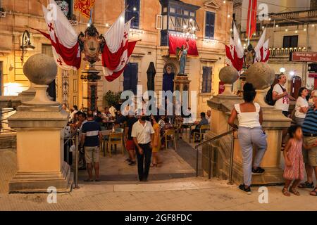 MOSTA, MALTA - Aug 15, 2021: Maltese Getränke, Snacks in der Open Air Bar . Straßendekoration von Flaggen. Covid-Vorsichtsmaßnahmen. Titularfest Assumptio Stockfoto