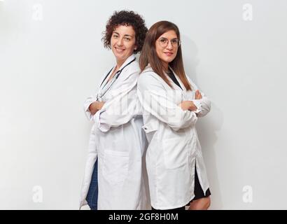 Zwei Ärztinnen posieren sich im Stehen zurück auf den Rücken Stockfoto