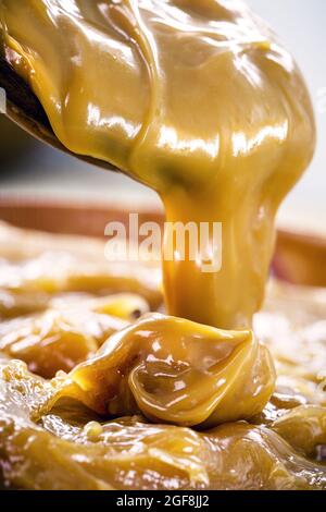 dulce de leche oder hausgemachtes Karamell tropft aus Holzlöffel, Makro-Foto von Lebensmitteln Stockfoto