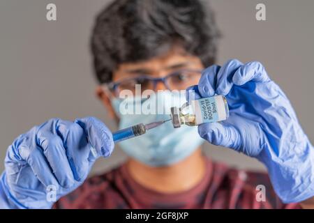 Nahaufnahme der Hände des Arztes, die den covid-19-Impfstoffverstärker mit einer Spritze halten - Konzept der Dosis von Coronavirus 3rd für geschwächte Immunmenschen. Stockfoto