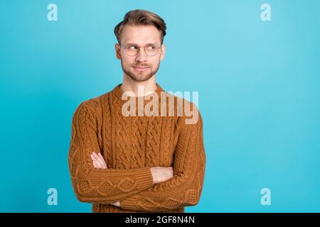 Foto von schweren verträumten jungen Mann suchen leeren Raum halten Arme auf blauem Hintergrund isoliert gefaltet Stockfoto