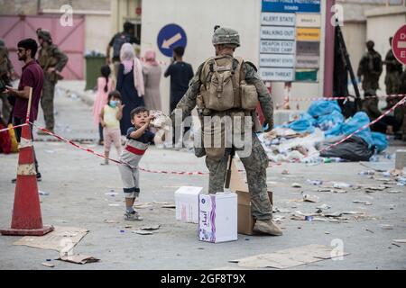 Kabul, Afghanistan. August 2021. Eine US-Marine mit dem Special Purpose Marine Air-Ground Task Force/Crisis Response Team übergibt Kindern, die auf die Evakuierung am Hamid Karzai International Airport warten, während der Operation Allies Refuge am 20. August 2021 in Kabul, Afghanistan, Mahlzeiten verzehrfertig. Quelle: Planetpix/Alamy Live News Stockfoto