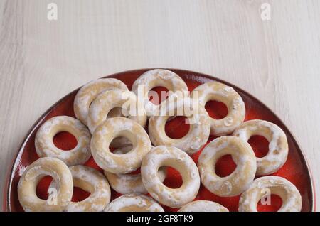 Glasierte Bagels in rotem Teller auf heller Holzoberfläche. Platz für Ihren Text Stockfoto