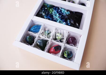 Weiße Geschenkschachtel mit handgefertigten Pralinen. Geometrisches und Raumdesign. Box auf einem hellen Hintergrund. Süßigkeiten und Süßigkeiten aus nächster Nähe Stockfoto