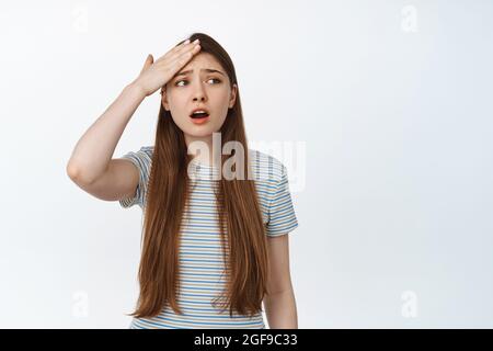 Besorgt Mädchen vergessen smth. Junge Frau hält die Hand auf die Stirn, schaut aufgeregt zur Seite, erinnert euch an etwas, hat Probleme, steht vor weißem Hintergrund Stockfoto