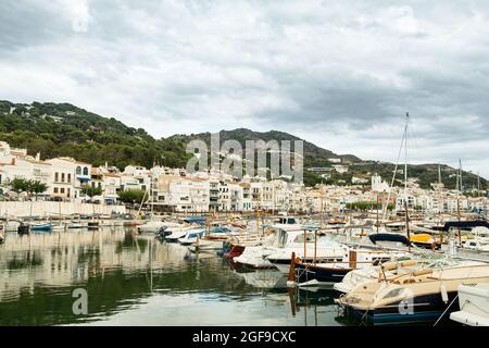 Blick auf die kleine spanische Stadt Port de la Selva Hafen an der Costa Brava in Katalonien, mit kleinen weißen Fischerbooten an einem bewölkten Sommertag während zu Stockfoto