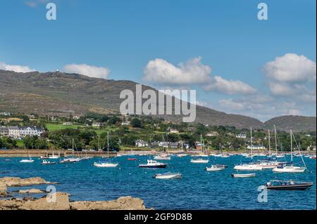 Schull, West Cork, Irland. August 2021. Die Sonne scheint auf vertäuten Booten im Schuller Hafen, mit dem Berg Gabriel im Hintergrund. Stockfoto