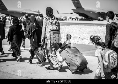 Ein Kind schaut auf das Flugzeug, während es während einer Evakuierung am Hamid Karzai International Airport, Kabul, Afghanistan, im August 24, auf seinen Flug zuläuft. US-Dienstmitglieder unterstützen das Außenministerium bei einer geordneten Abseichung von designiertem Personal in Afghanistan. (USA Marine Corps Foto von Sgt. Samuel Ruiz). Stockfoto