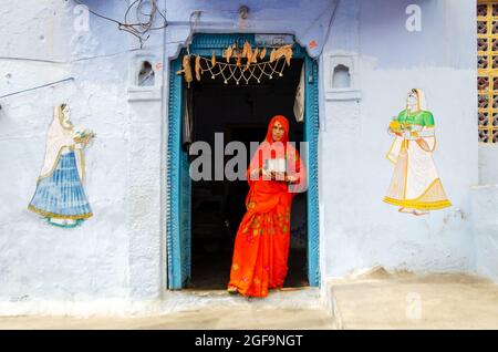 Jodhpur, Indien - 28. Februar 2018: Indische Frau, die vor der Tür in der blauen Stadt Jodhpur steht. Stockfoto