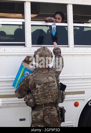 Flugplatz Ali Al Salem, Kuwait. August 2021. Eine Militärpolizei der US-Luftwaffe mit der 16. Militärpolizeibrigade gibt afghanischen Flüchtlingen während der Operation Allies Refuge bei ihrer Ankunft am Ali Al Salem Airbase am 23. August 2021 in Ali Al Salem, Kuwait, Wasserflaschen aus. Quelle: Planetpix/Alamy Live News Stockfoto