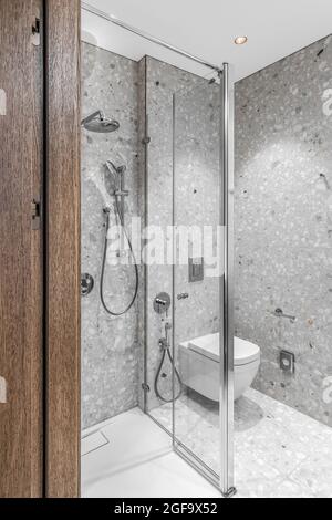 Modernes, minimalistisches Badezimmer mit Chrom-Accessoires im Badezimmer und grauen Fliesen Stockfoto