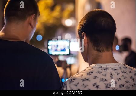 Hinter den Kulissen. Der Filmregisseur überwacht und steuert die Aufnahme des Films auf dem lcd-Display vom Filmmontagestudio im Freien aus. Analog A Stockfoto