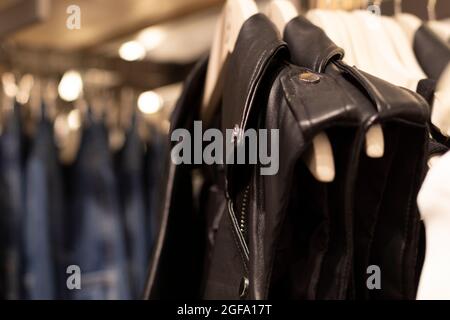 Eine schwarze Lederjacke mit Reißverschlüssen, ärmellose, typische Biker-Jacke. Hängen an einem Kleiderbügel in einem Geschäft. Stockfoto