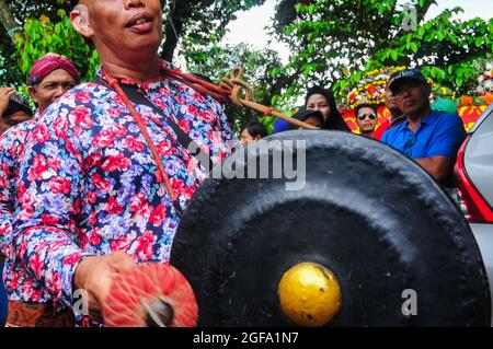 Ein gong-Spieler in einer Gruppe von Musikern, der die Kunst des Reogs begleitet, während er am Karneval teilnimmt. Stockfoto