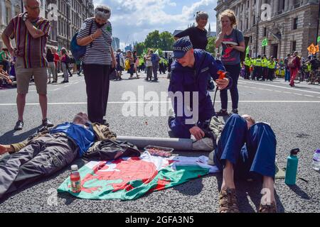 London, Großbritannien. August 2021. Die Polizei bereitet sich darauf vor, Extinction Rebellion-Demonstranten zu entfernen und zu verhaften, die sich an der Straße vor HM Revenue & Customs festhielten. Die Demonstranten versammelten sich in Westminster zum zweiten vollen Tag ihrer zweiwöchigen Kampagne, Impossible Rebellion, und forderten die britische Regierung auf, in der Klima- und Umweltkrise sinnvoll zu handeln. (Kredit: Vuk Valcic / Alamy Live News) Stockfoto