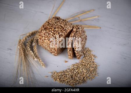 Vollkornbrot mit Weizen, Roggen und Sonnenblumenkernen auf einem grauen Holzbrett Stockfoto