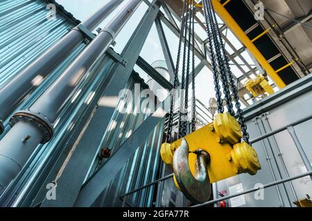 Gelber Haken und Kette des Brückenkrans der Fabrik. Diagonale Linien Stockfoto