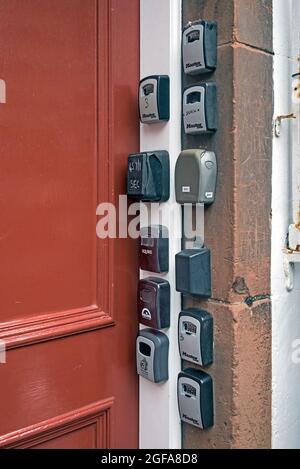 Elf Schlüsseltresore für kurzfristige oder Airbnb-Zimmer am Eingang zu einem Mietshaus im Lawnmarket in der Altstadt von Edinburgh. Stockfoto