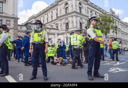 London, Großbritannien. August 2021. Die Polizei bereitet sich darauf vor, Extinction Rebellion-Demonstranten zu entfernen und zu verhaften, die sich an der Straße vor HM Revenue & Customs festhielten. Die Demonstranten versammelten sich in Westminster zum zweiten vollen Tag ihrer zweiwöchigen Kampagne, Impossible Rebellion, und forderten die britische Regierung auf, in der Klima- und Umweltkrise sinnvoll zu handeln. (Kredit: Vuk Valcic / Alamy Live News) Stockfoto