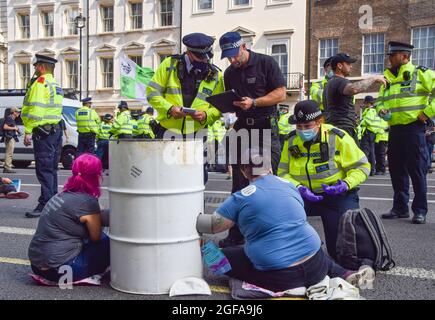 London, Großbritannien. August 2021. Die Polizei bereitet sich darauf vor, Extinction Rebellion-Demonstranten zu entfernen und zu verhaften, die sich auf der Straße vor HM Revenue & Customs an einem Fass festhielten. Die Demonstranten versammelten sich in Westminster zum zweiten vollen Tag ihrer zweiwöchigen Kampagne, Impossible Rebellion, und forderten die britische Regierung auf, in der Klima- und Umweltkrise sinnvoll zu handeln. (Kredit: Vuk Valcic / Alamy Live News) Stockfoto