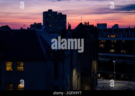 Edinburgh, Schottland, Großbritannien, 24. August 2021. UK Wetter: Wenn die Sonne mit rosa Wolken über den Dächern von Leith untergeht Stockfoto