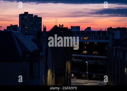 Edinburgh, Schottland, Großbritannien, 24. August 2021. UK Wetter: Wenn die Sonne mit rosa Wolken über den Dächern von Leith untergeht Stockfoto