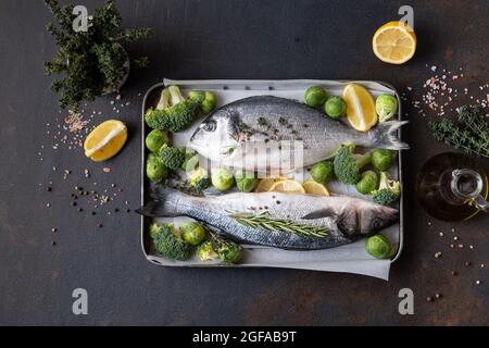 Frischer roher dorado- und sibas-Fisch mit Gewürzen. Zutaten zum Kochen oder Grillen auf Schneidebrett. Draufsicht, Kopierbereich Stockfoto